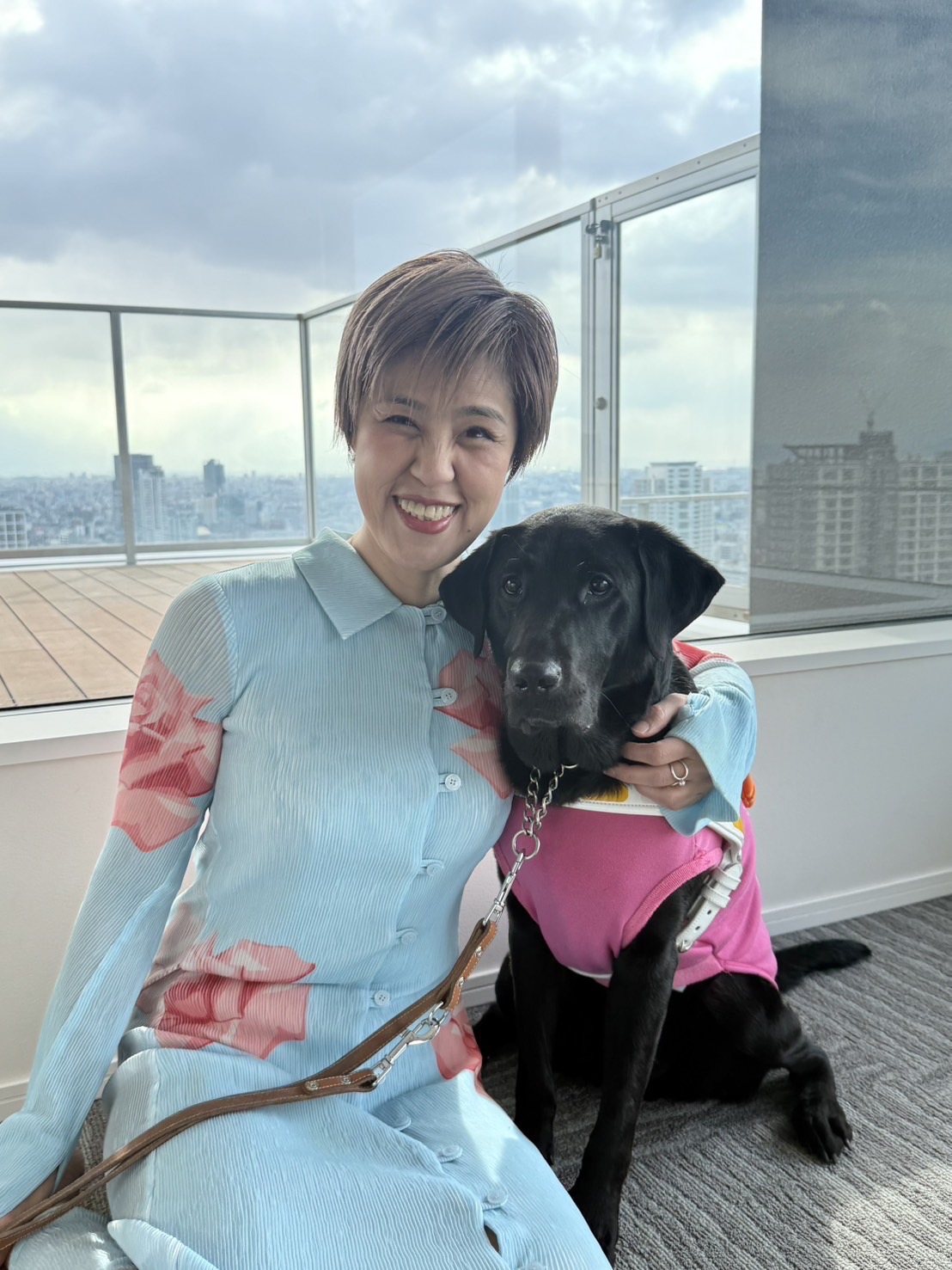 浅井純子が座って盲導犬を抱いてほほ笑んでいる写真