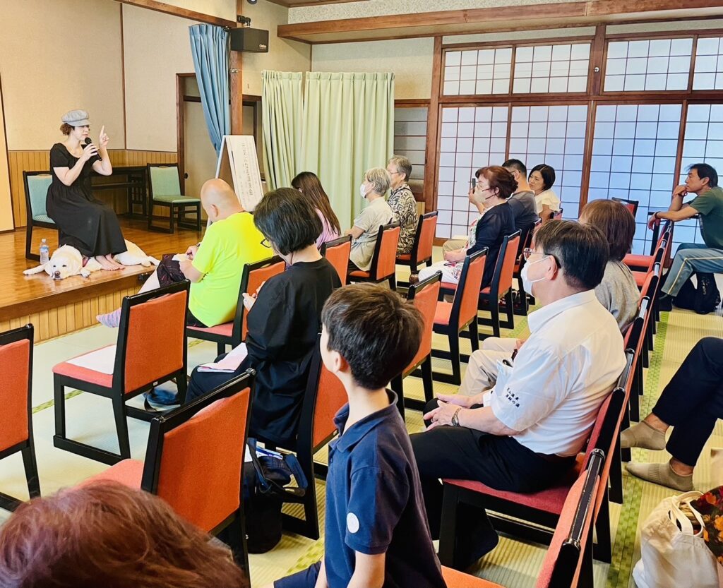 講演会のステージで盲導犬のヴィヴィッドくんと一緒に語っている浅田純子さん（横から撮影）